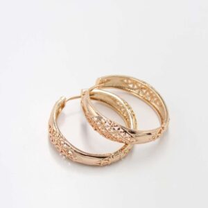 Gold hoop earrings with intricate engraved floral patterns on a smooth background.