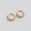 Gold-plated hoop earrings with intricate chain details and bold yellow gemstone centers, displayed on a neutral background.