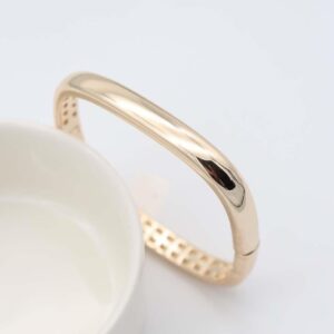 Golden Elegance Bangle Bracelet with a smooth, polished gold-plated surface and hinged clasp.